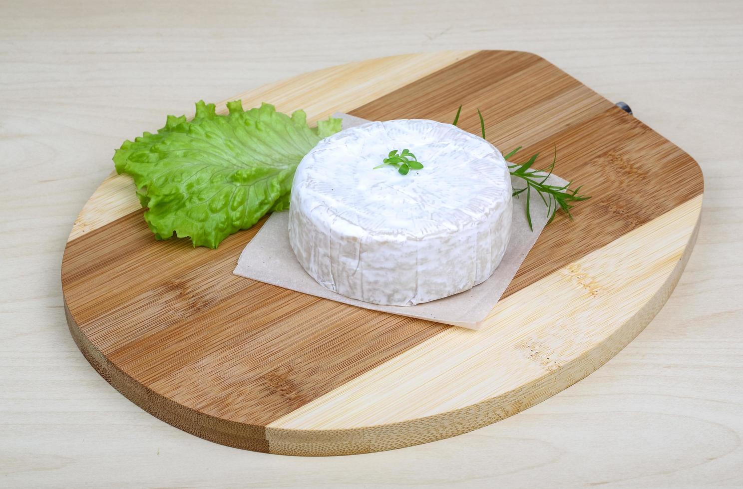 Camembert cheese on wooden board and wooden background photo
