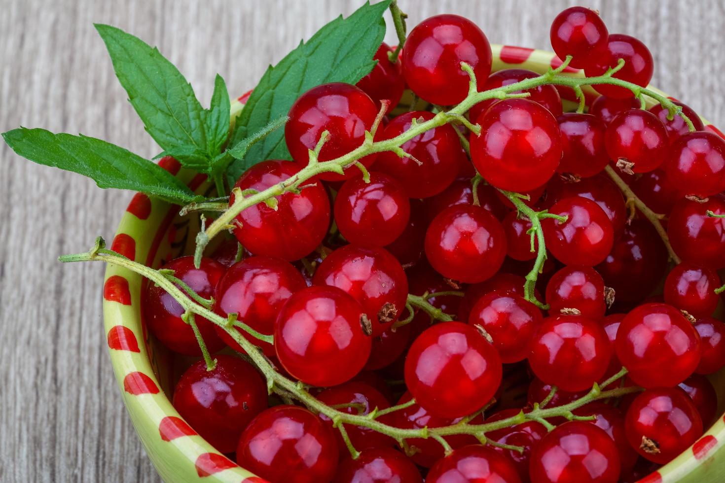 Red currant in a bowl on wooden background photo