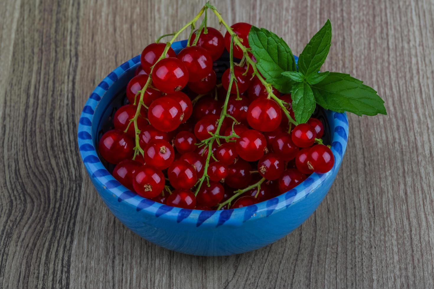 Red currants in a bowl on wooden background photo