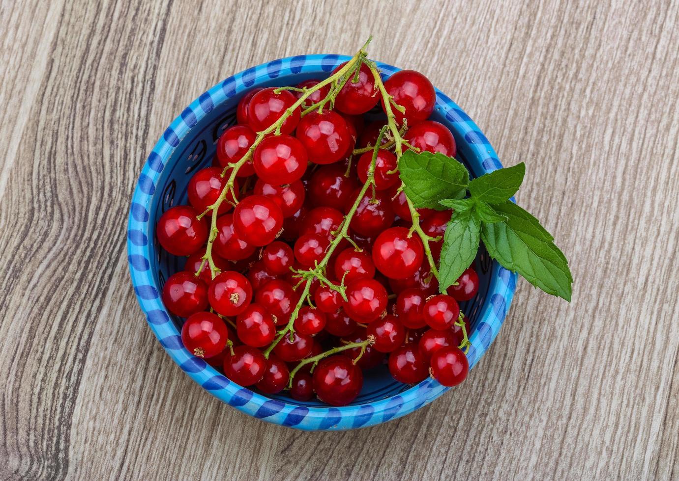 Red currants in a bowl on wooden background photo