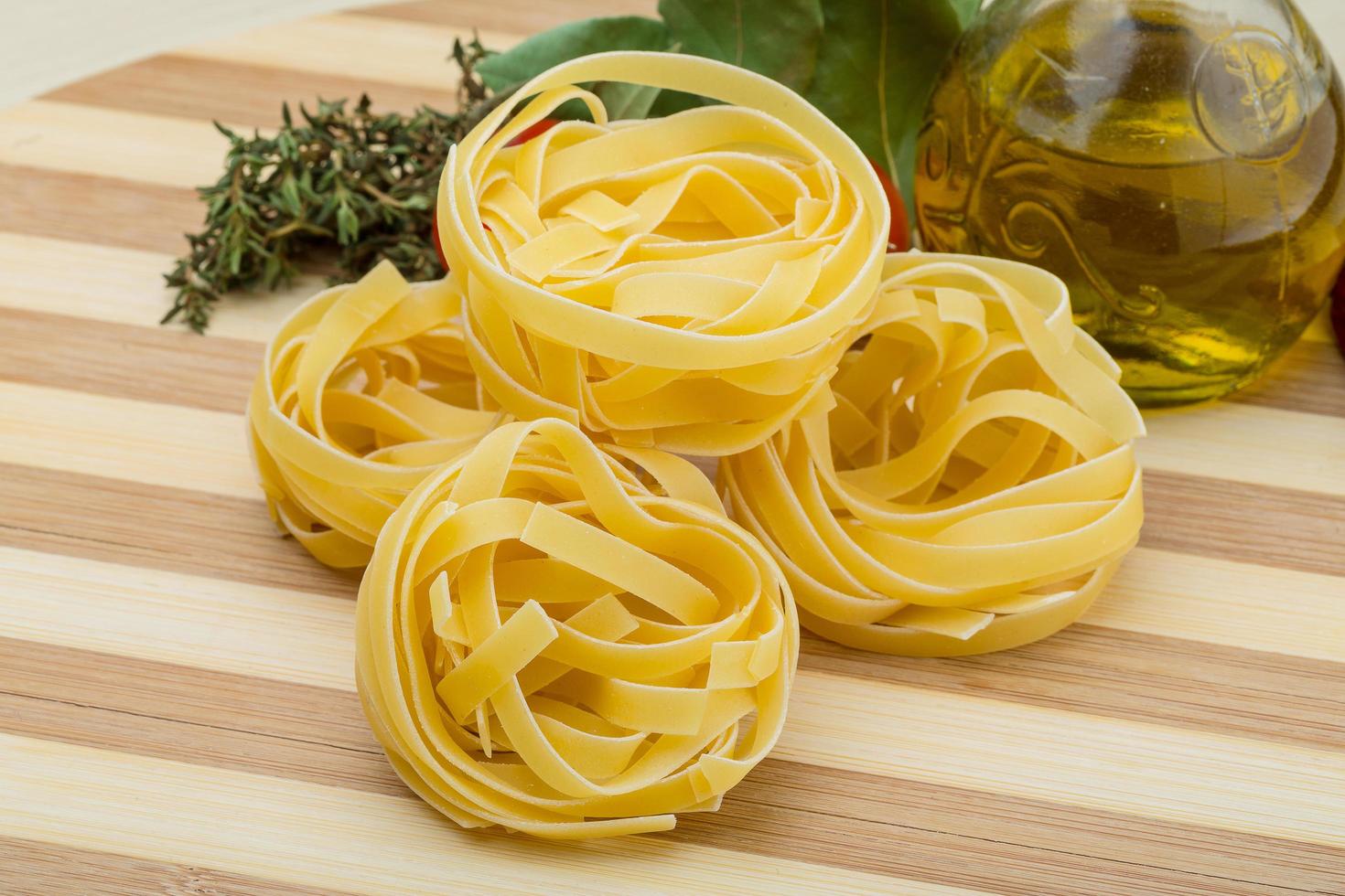 Raw fettuccine on wooden board and wooden background photo