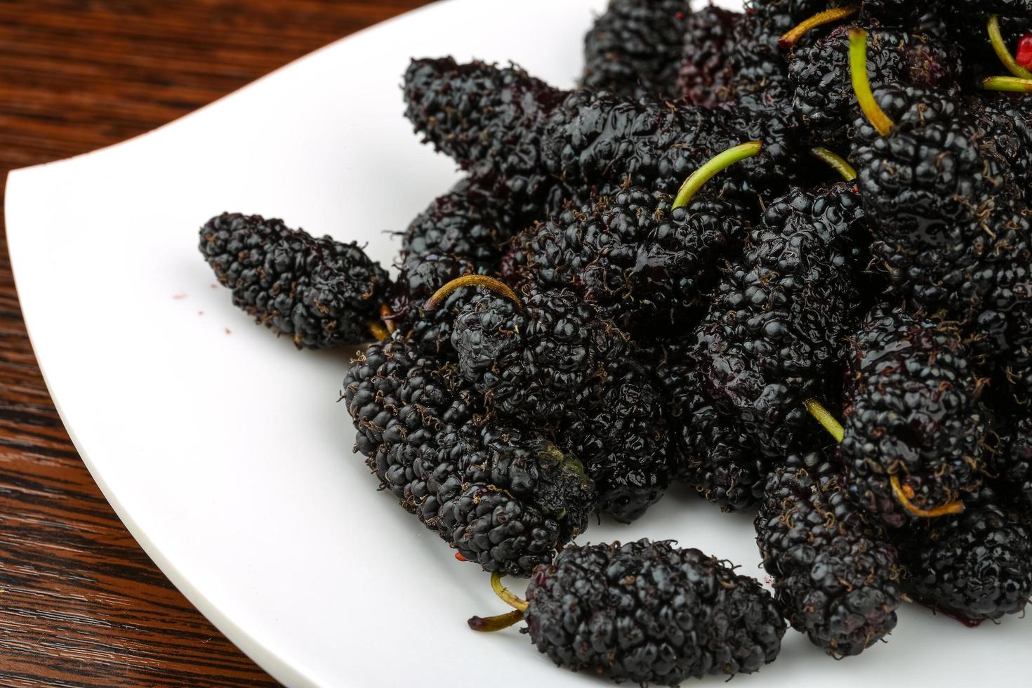 Mulberry on the plate and wooden background photo