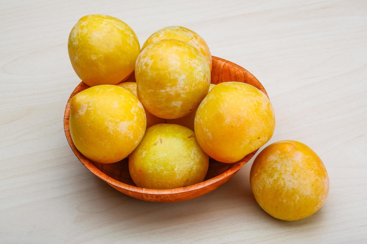 Yellow plums in a bowl on wooden background photo