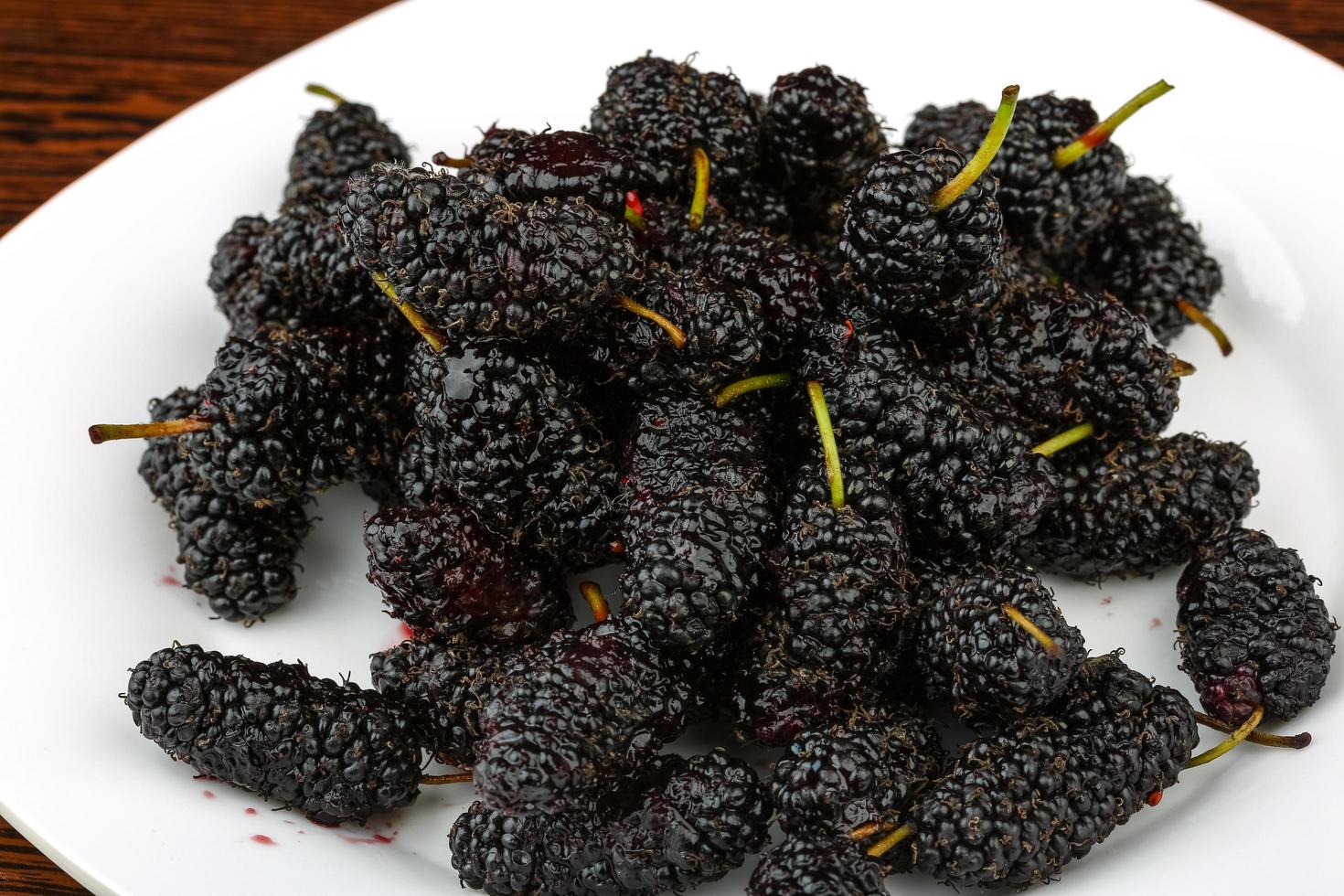 Mulberry on the plate and wooden background photo