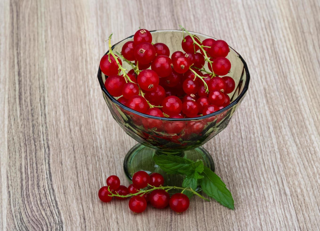 Red currant in a bowl on wooden background photo