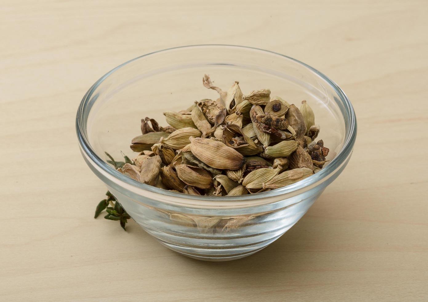 Cardamom in a bowl on wooden background photo