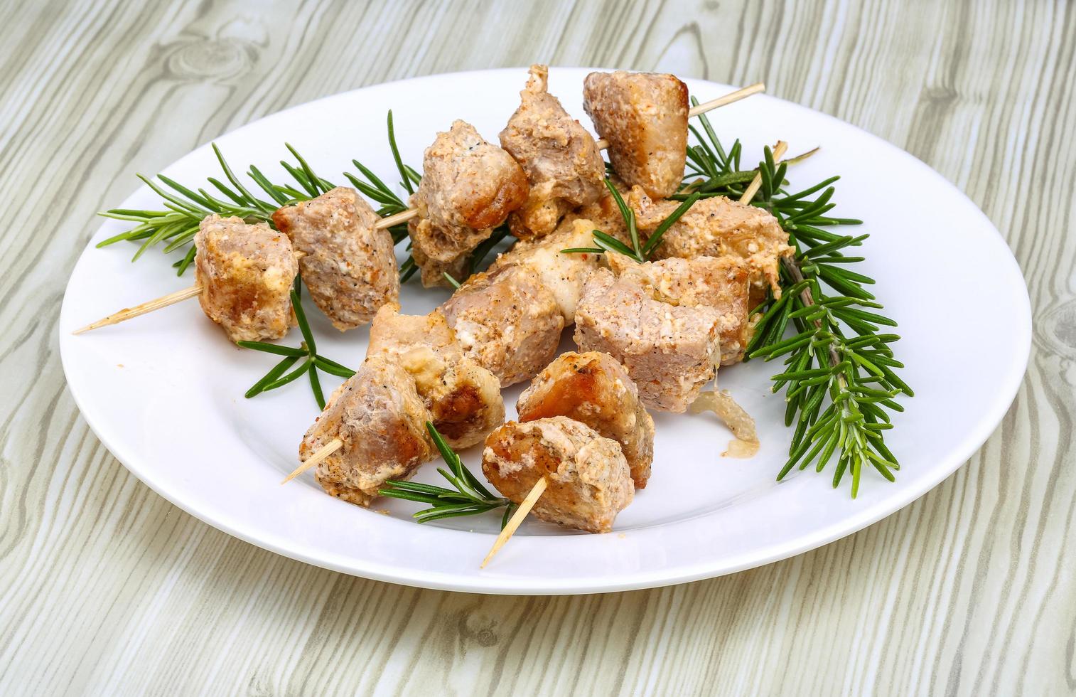 Chicken skewers on the plate and wooden background photo