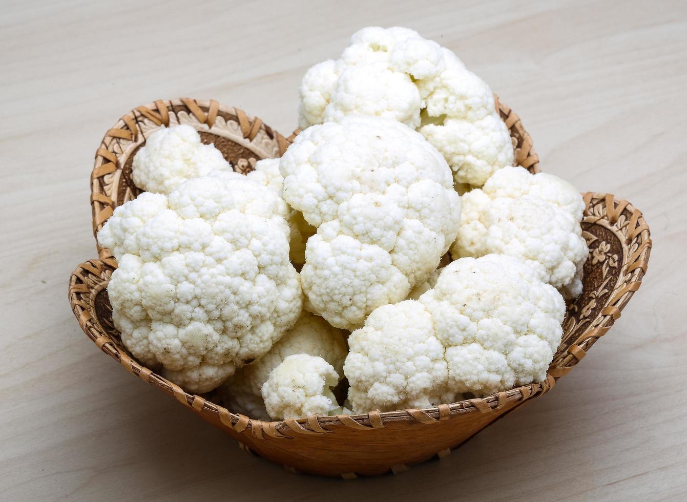 Cauliflower in a basket on wooden background photo