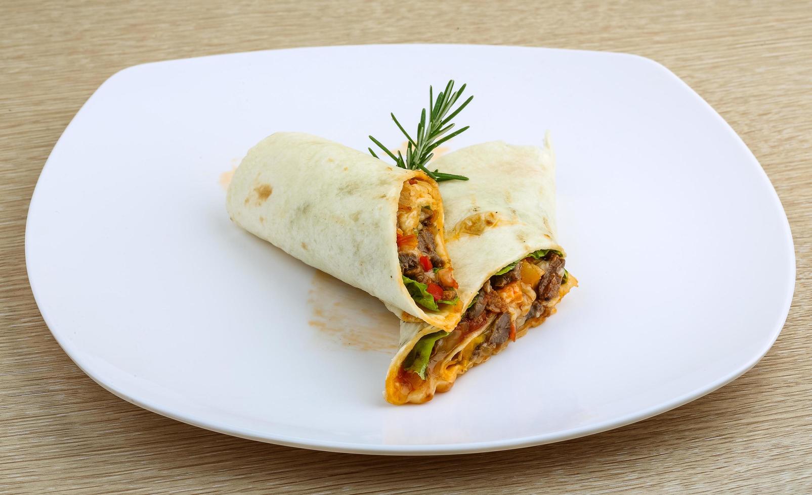 Wrap tortilla on the plate and wooden background photo