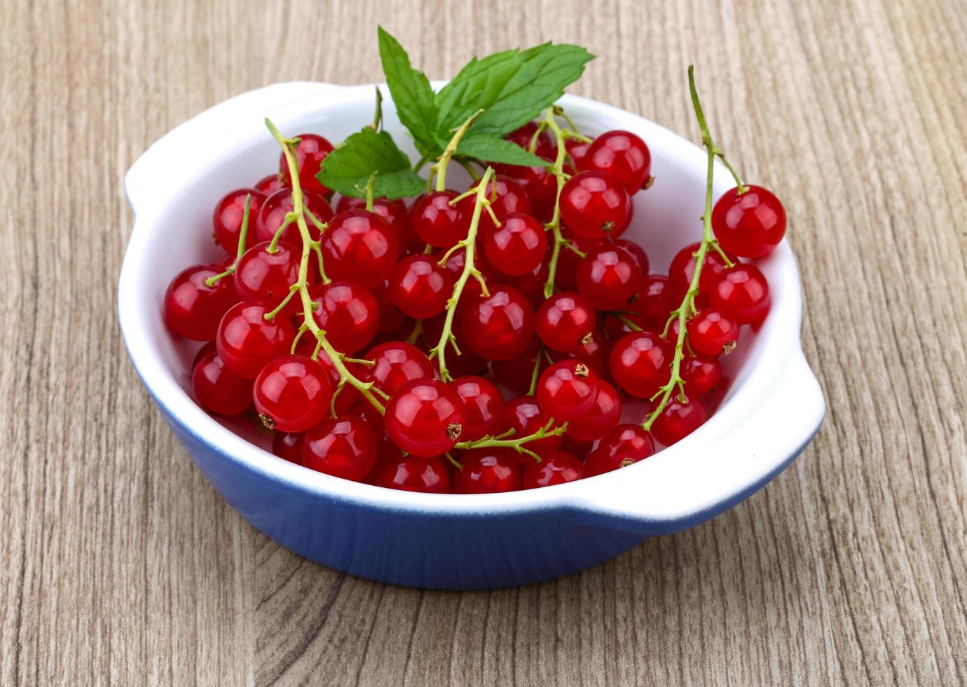 Red currants in a bowl on wooden background photo