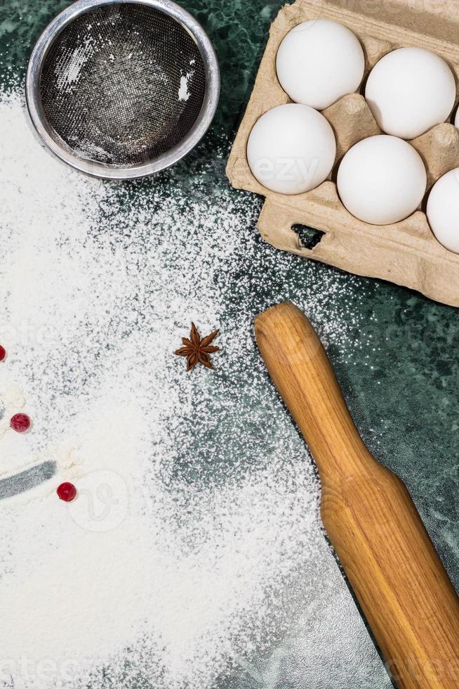 flour, berries and anise star spices as a decoration and rolling pin, eggs, strainer photo