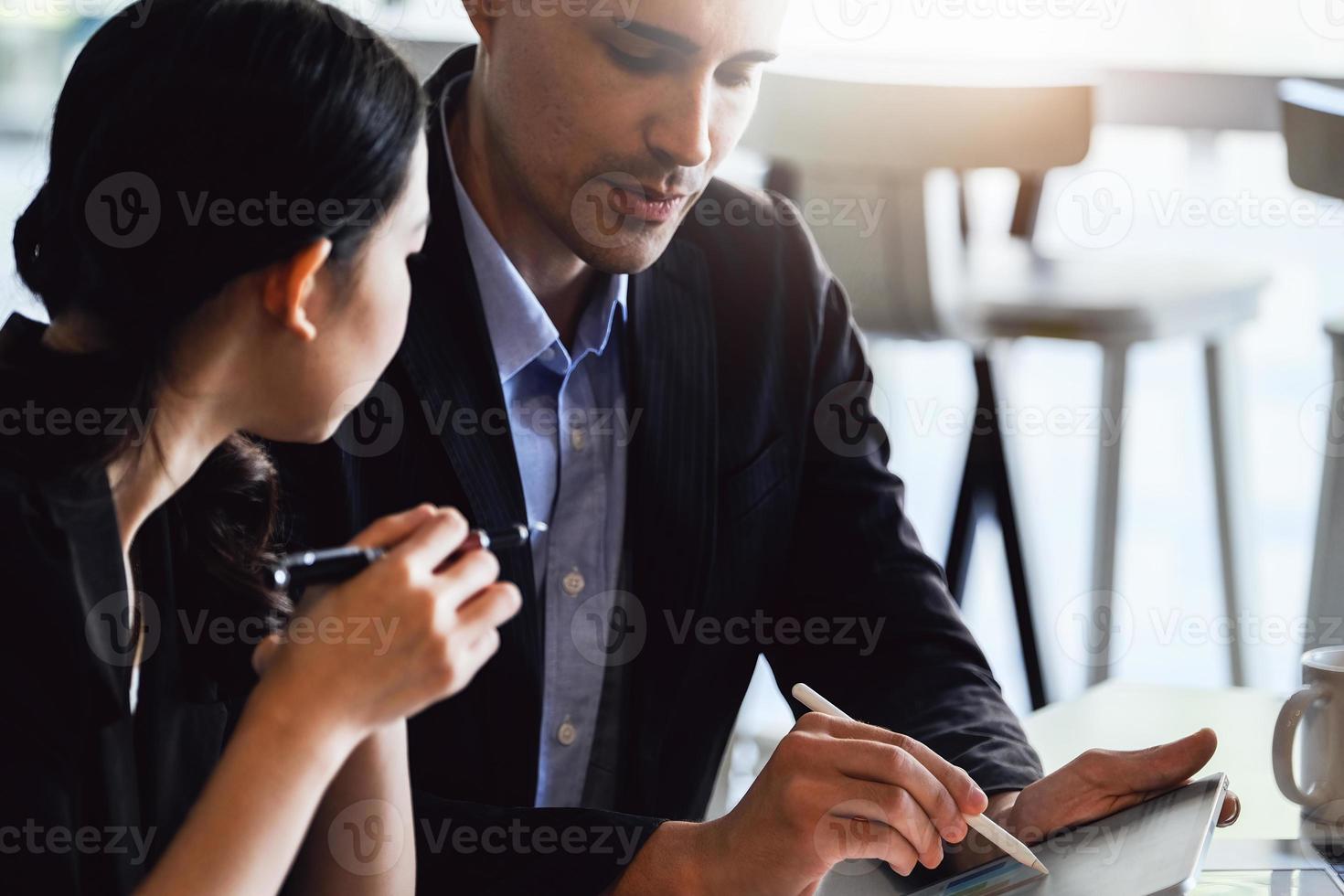 en la consulta, un asesor masculino usa un bolígrafo para señalar una tableta para explicar la reestructuración de ganancias a las propietarias de empresas. foto