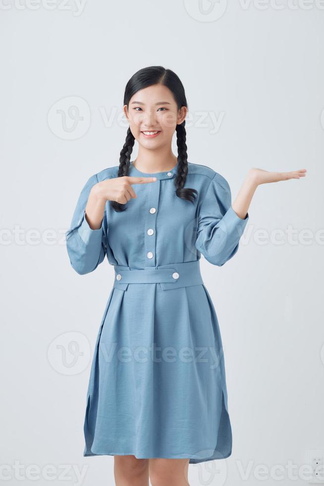 Young beautiful asian woman smiling cheerful presenting and pointing with palm of hand looking at the camera. photo