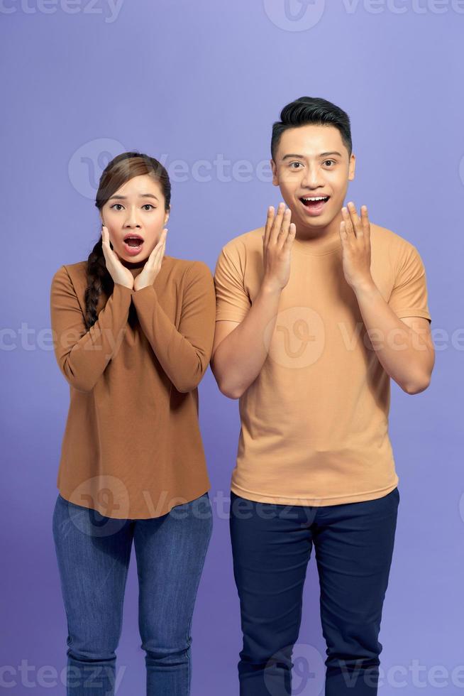 Photo of cute excited young loving couple standing isolated over purple wall background.