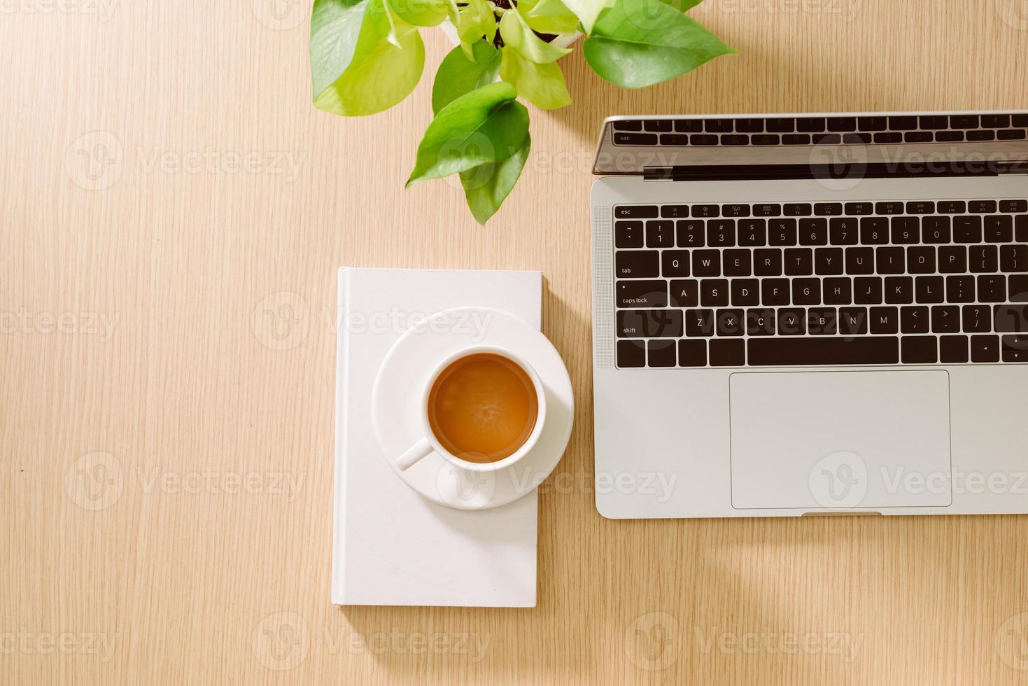 Office desk table with laptop, smart phone, cup of coffee, pen, pencil and notebook. Office supplies and gadgets on desk table. Working desk table concept. photo