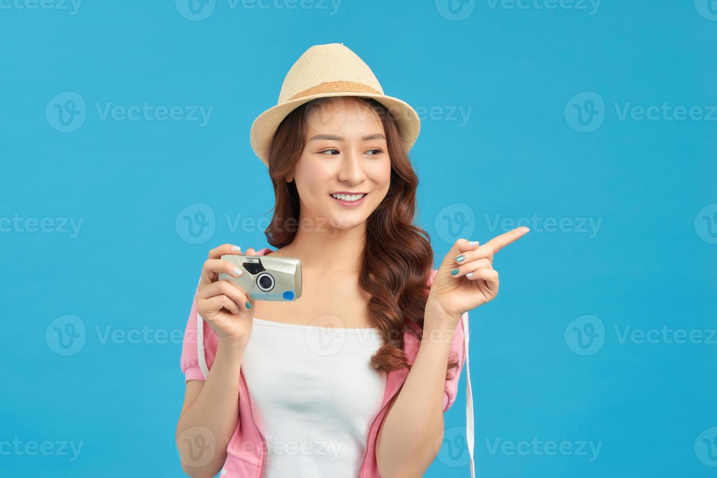 Attractive energetic Asian woman happily holding cemara isolated on blue studio background photo