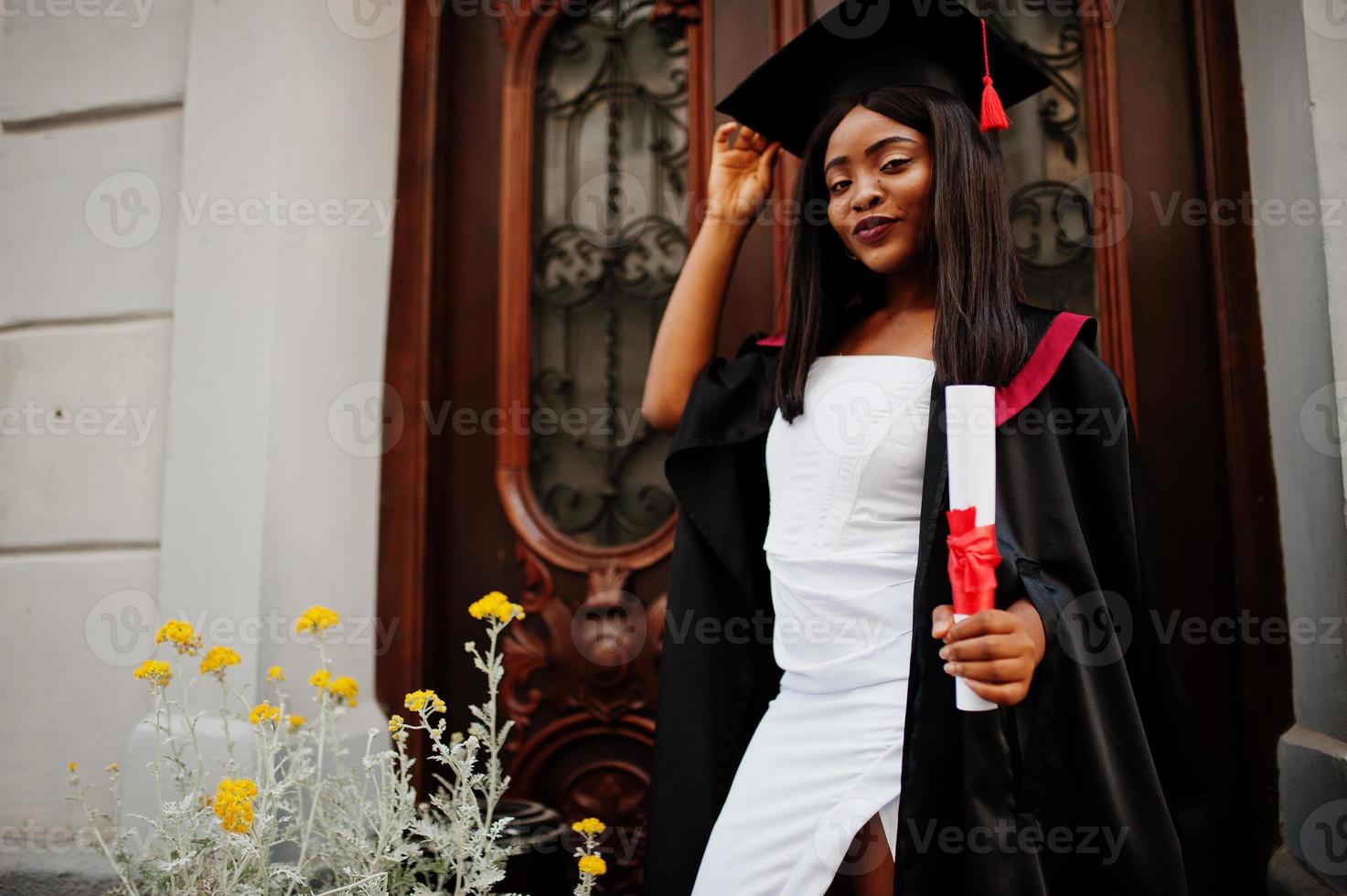 joven estudiante afroamericana con diploma posa al aire libre. foto