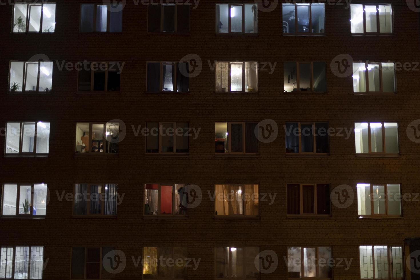 Windows in house at night. Light from windows of apartments. Building is in dark. Night City. photo