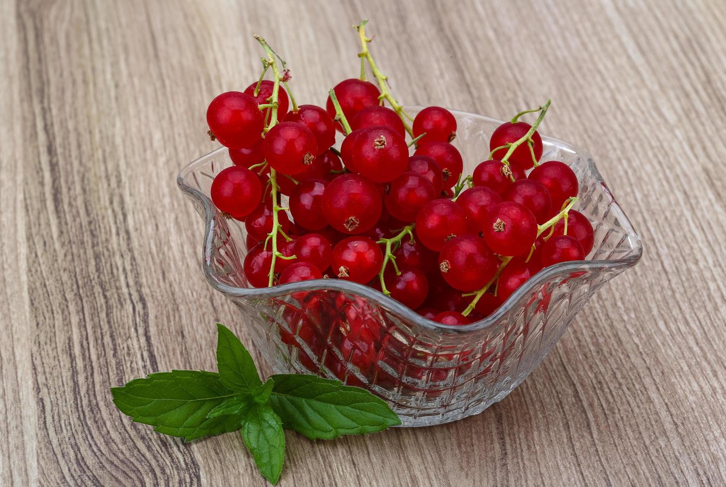Red currant in a bowl on wooden background photo