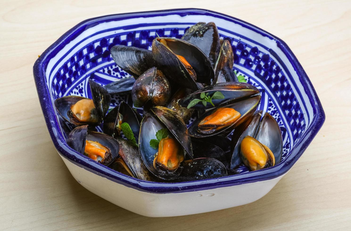 mejillones hervidos en un recipiente sobre fondo de madera foto