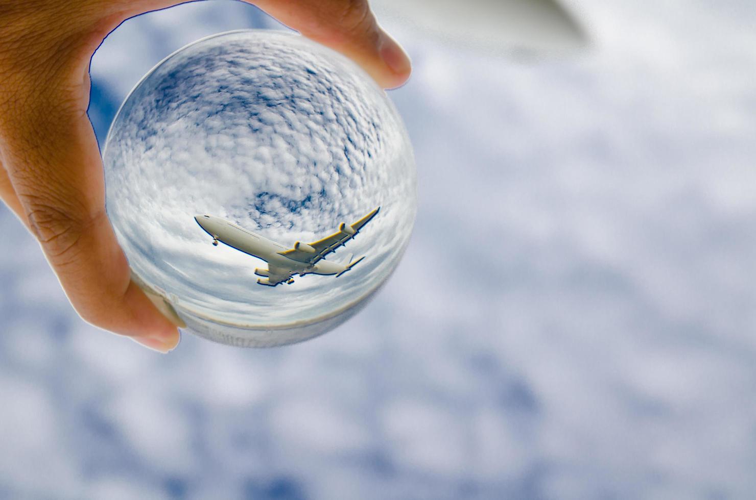 Airplane flying on cloudy sky photography in glass ball. photo