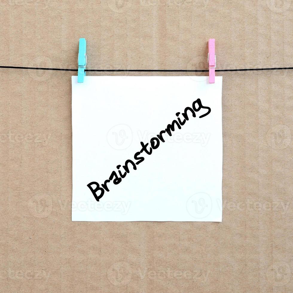 Brainstorming. Note is written on a white sticker that hangs with a clothespin on a rope on a background of brown cardboard photo