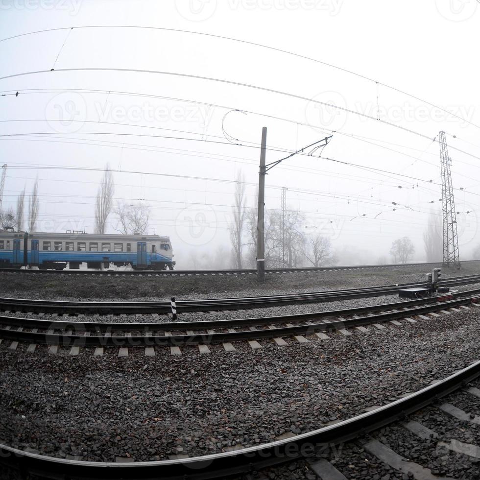 The Ukrainian suburban train rushes along the railway in a misty morning. Fisheye photo with increased distortion