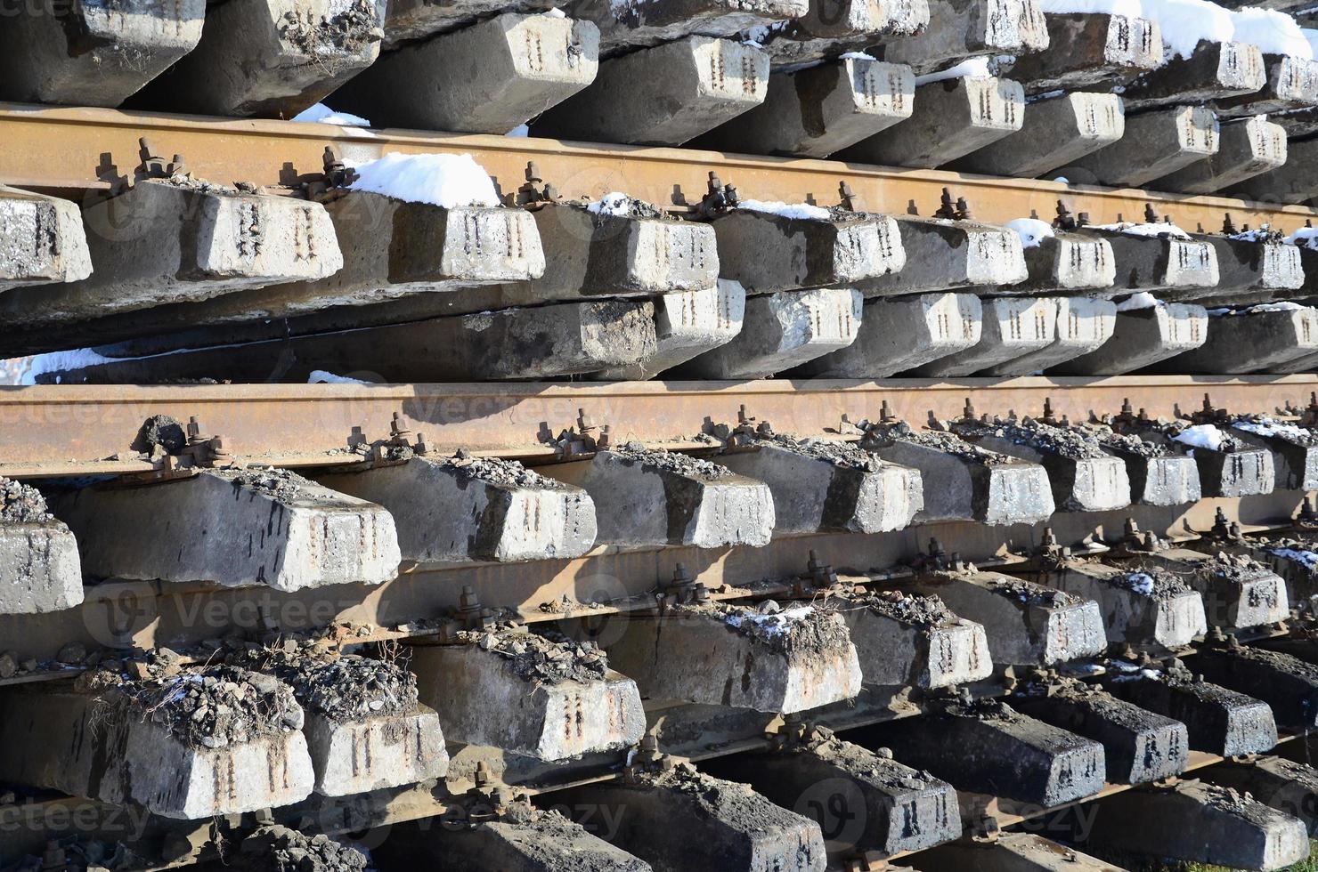 A lot of old rails and sleepers are stacked in a railway warehouse in winter. The concept of renewing a worn-out railway track photo