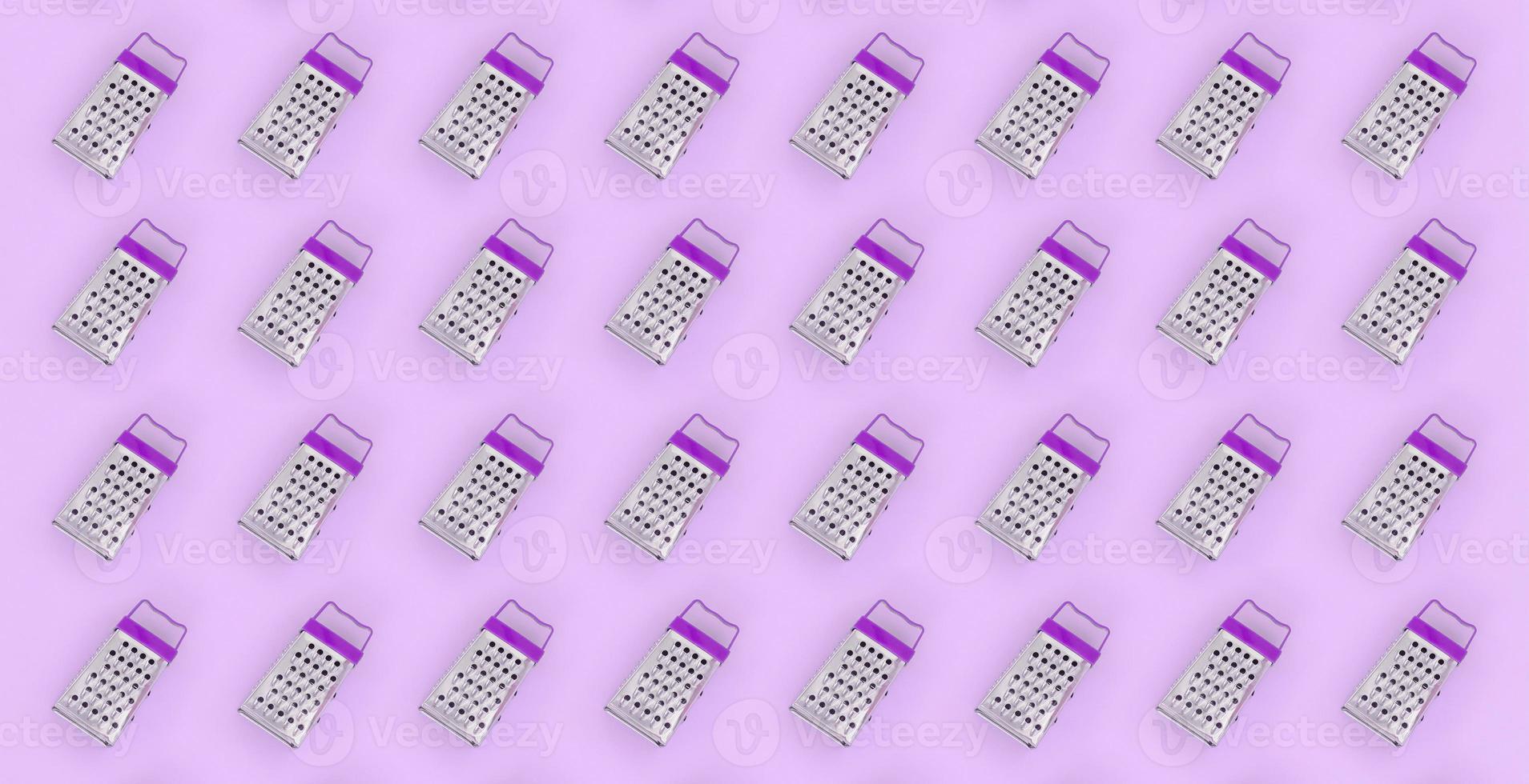 Small stainless steel graters lies on a pastel colored paper. Kitchen accessories. Tools for cooking. Flat lay top view photo
