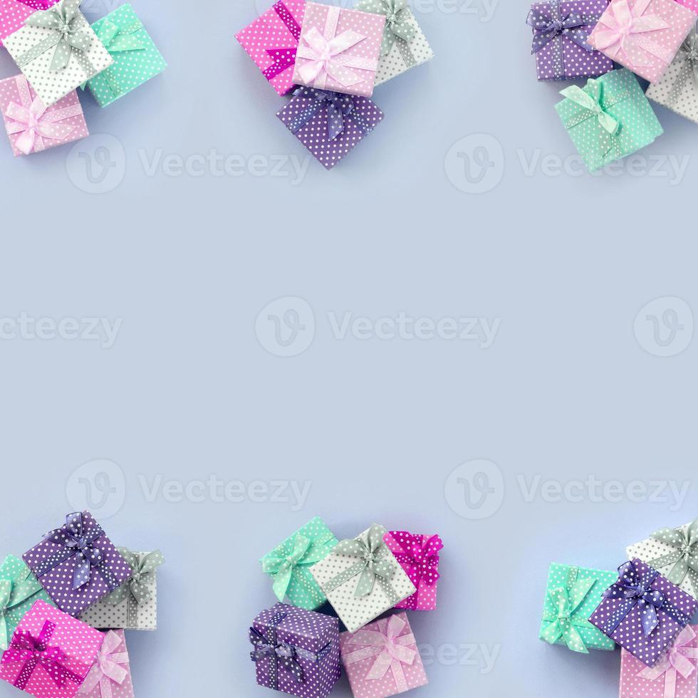 Piles of a small colored gift boxes with ribbons lies on a violet background photo