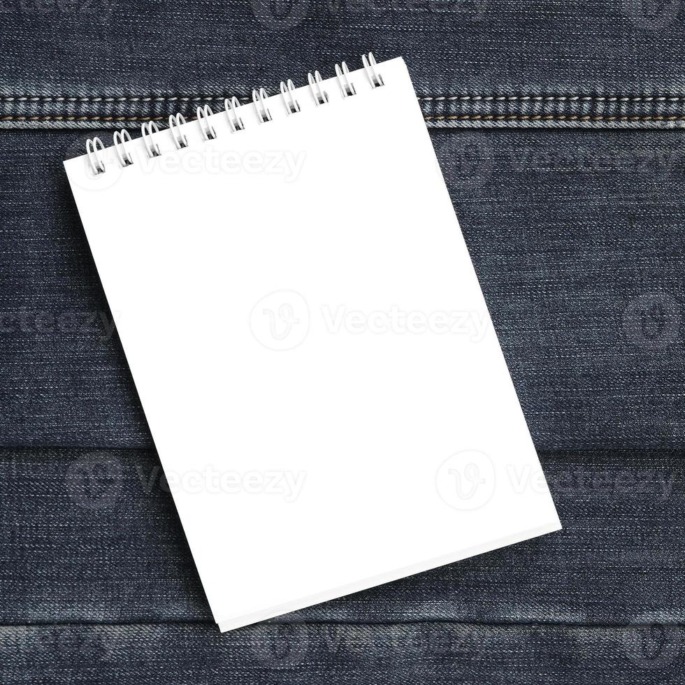 cuaderno blanco con páginas limpias sobre fondo de jeans azul oscuro. imagen con espacio de copia foto