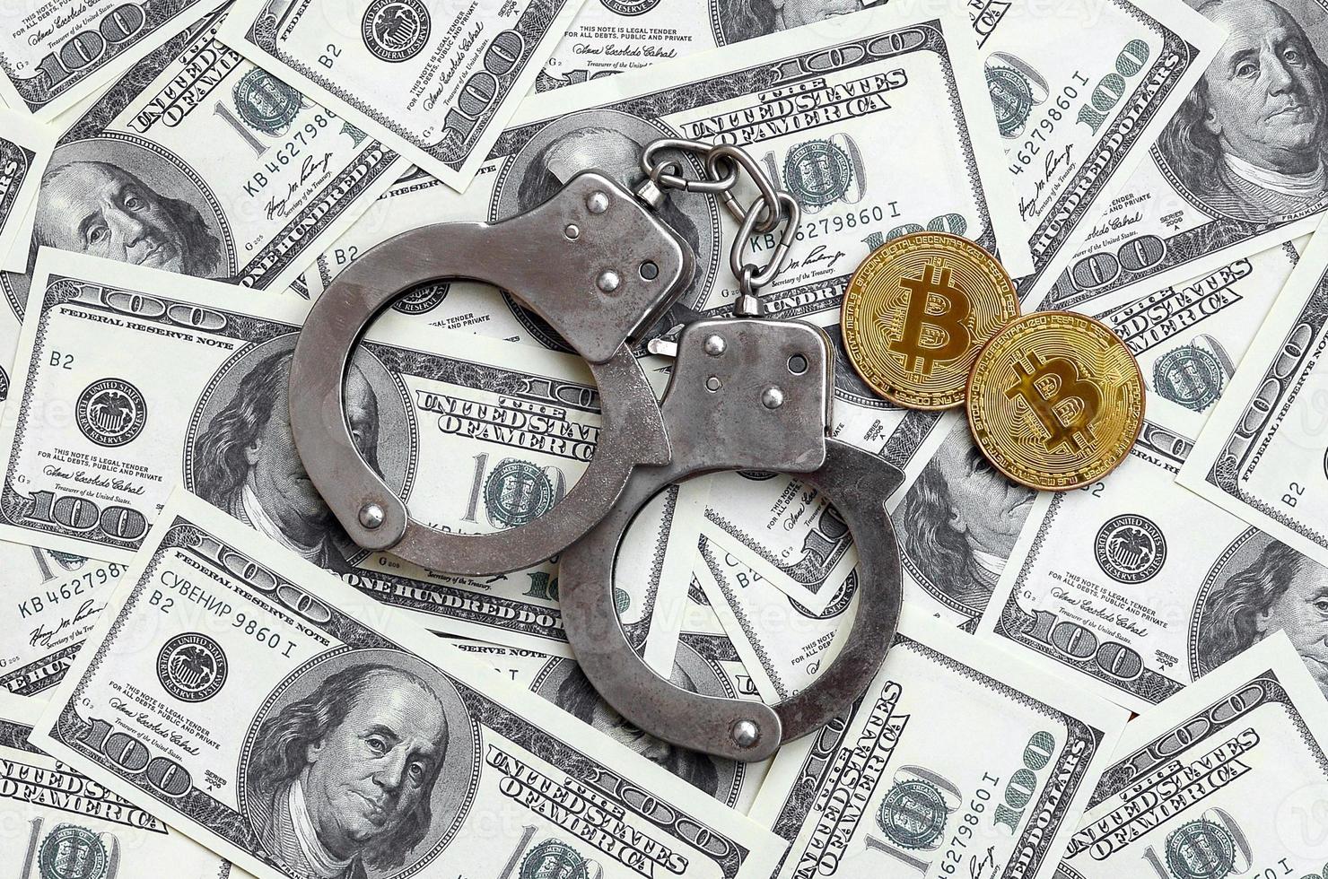 Police handcuffs and bitcoins lie on a large number of dollar bills. The concept of problems with the law during the illegal cryptocurrency mining and bitcoin operations photo