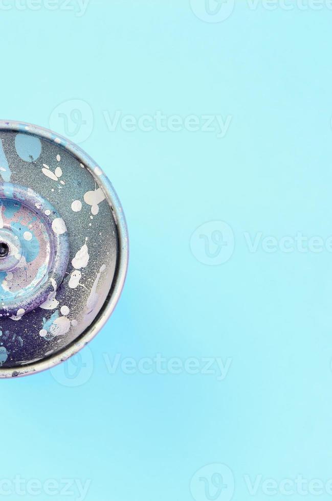 Used spray can with blue paint drips lie on texture background of fashion pastel blue color paper photo
