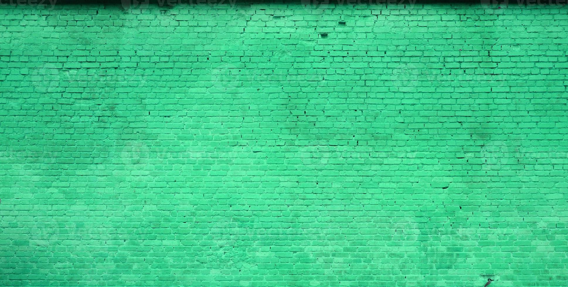 The texture of the brick wall of many rows of bricks painted in green color photo