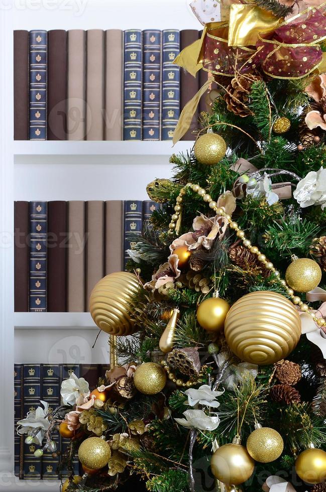 A beautiful decorated Christmas tree on the background of a bookshelf with many books of different colors. Christmas background image of the library photo