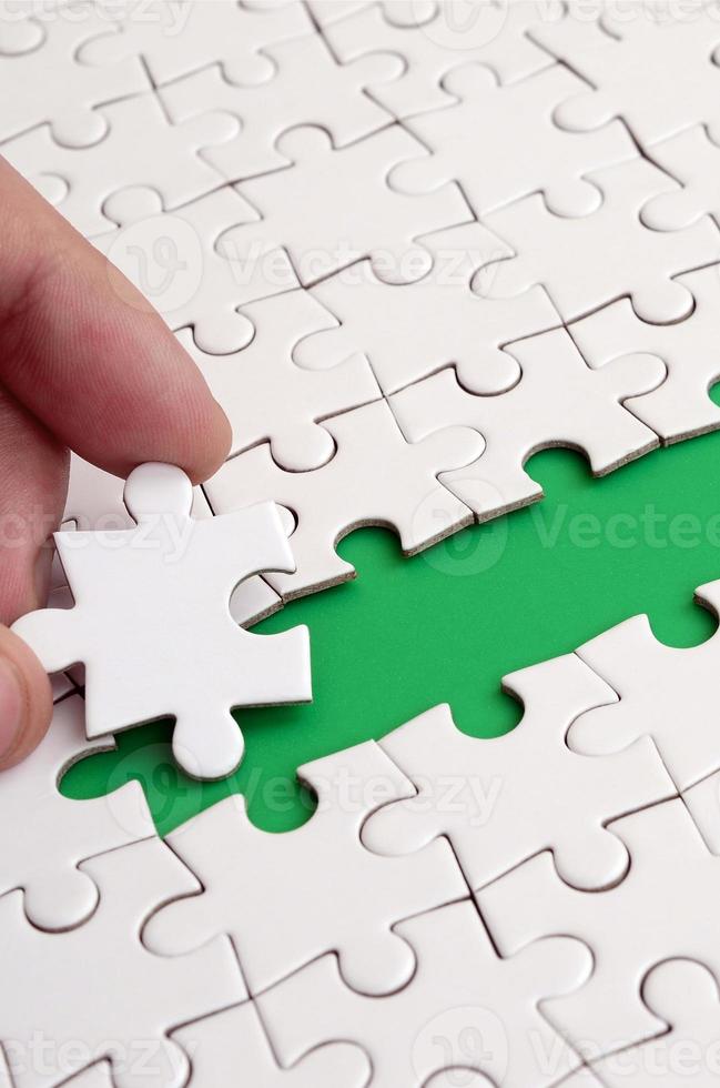 The human hand paves the way to the surface of the jigsaw puzzle, forming a green space. The concept of overcoming the difficulties on the way to success photo