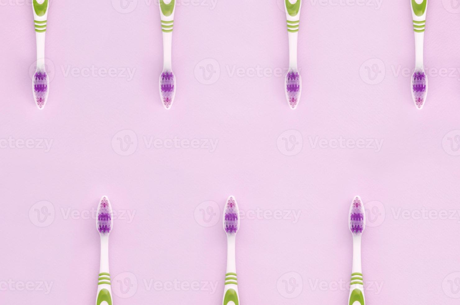 muchos cepillos de dientes yacen sobre un fondo rosa pastel foto
