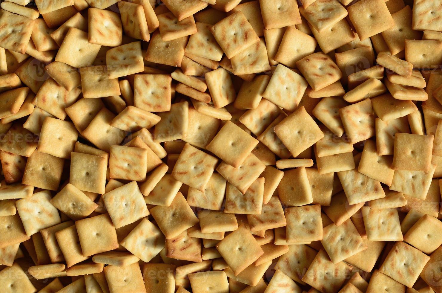 Background texture of small edible squares baked from dough and sprinkled with salt. A lot of salt cracker photo