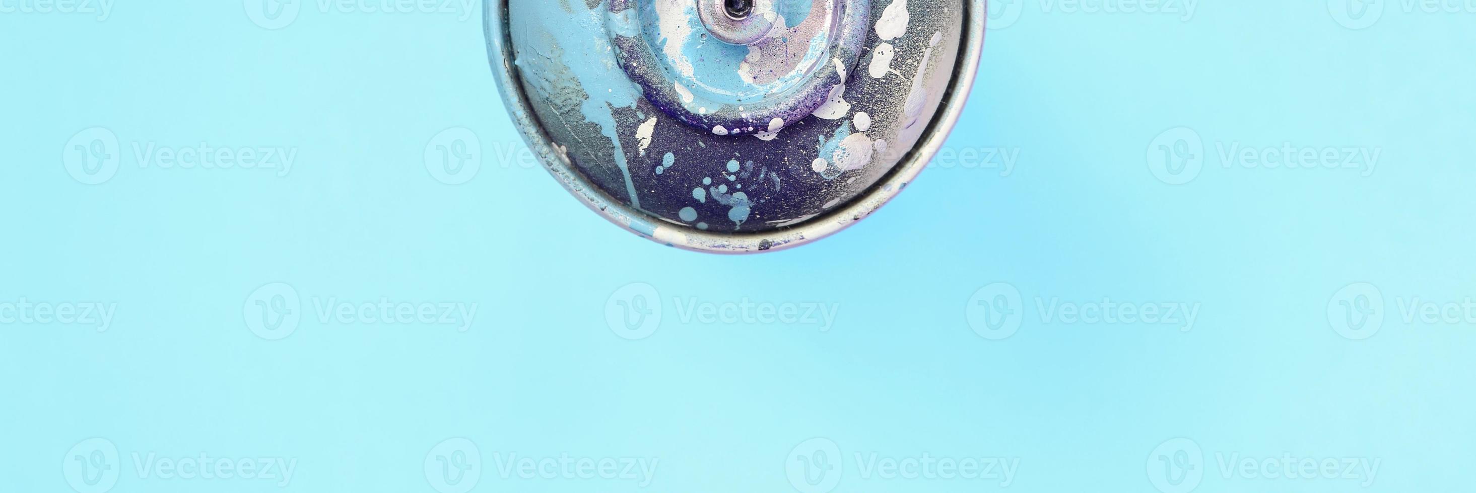 Used spray can with blue paint drips lie on texture background of fashion pastel blue color paper photo