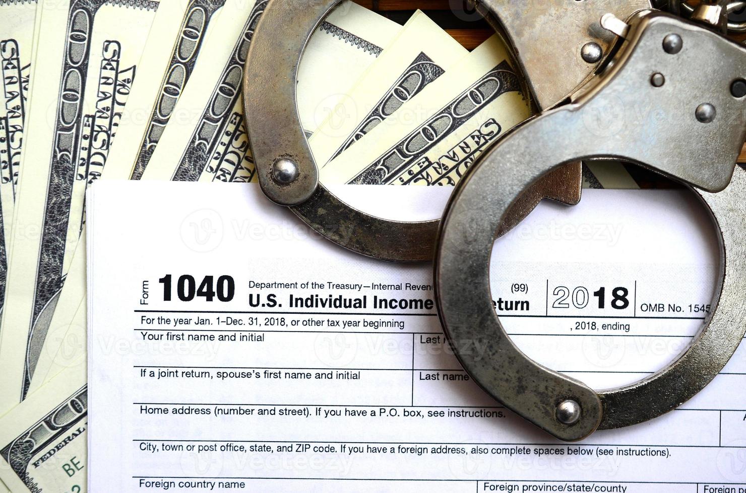 Police handcuffs lie on the tax form 1040. The concept of problems with the law in the aftermath of non-payment of taxes photo