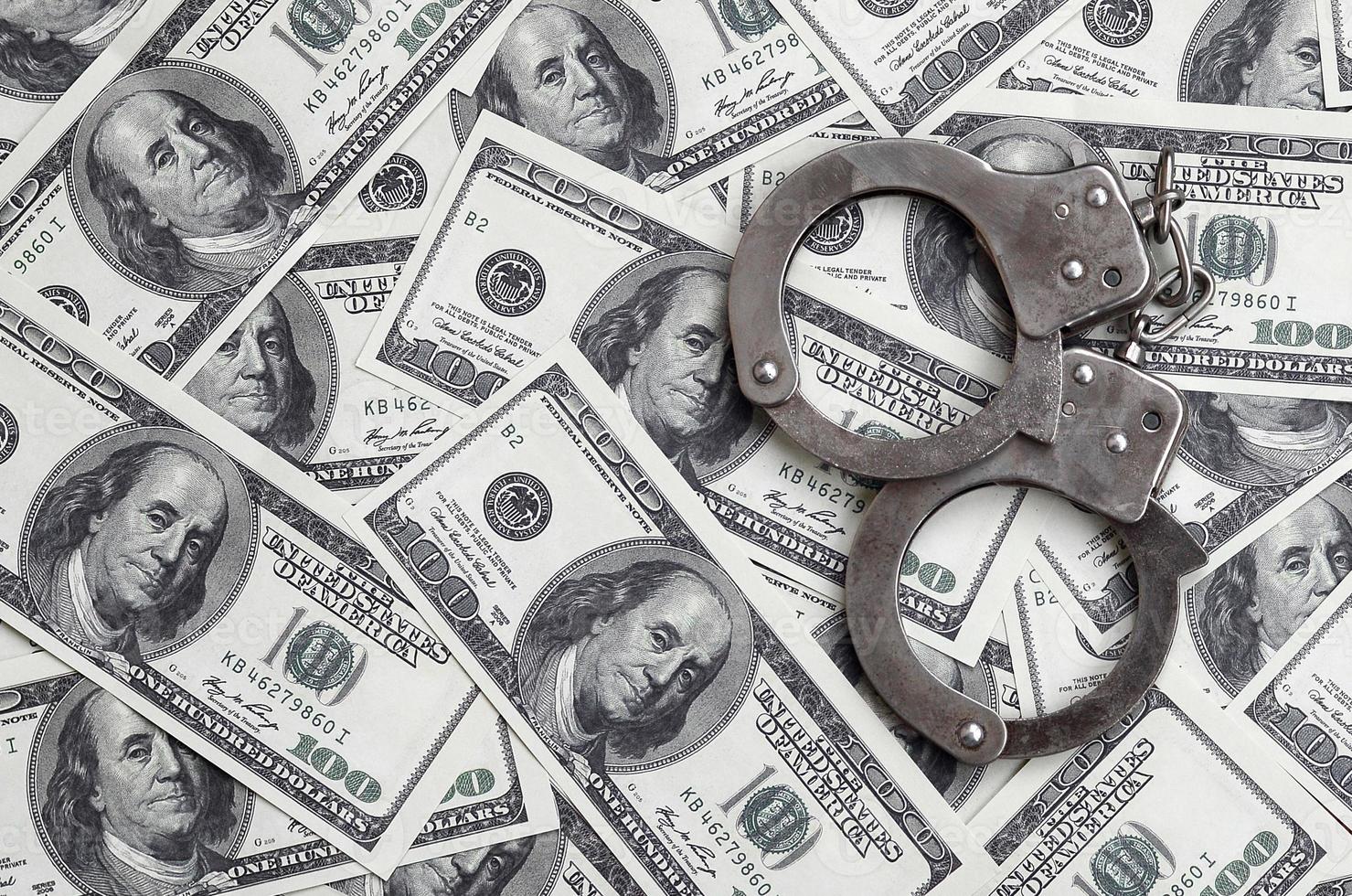 Police handcuffs lie on a lot of dollar bills. The concept of illegal possession of money, illegal transactions with US dollars. Economic Crime photo