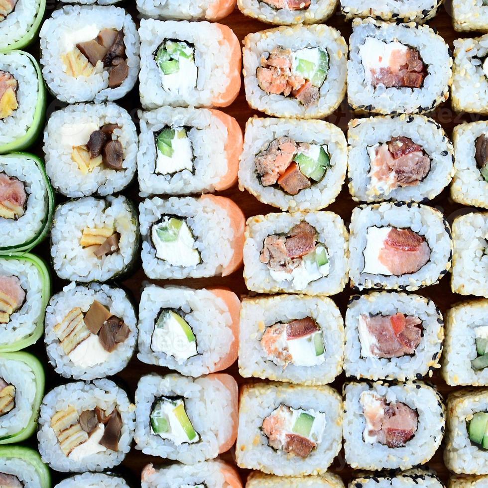 primer plano de muchos rollos de sushi con diferentes rellenos. toma macro de comida japonesa clásica cocinada. imagen de fondo foto