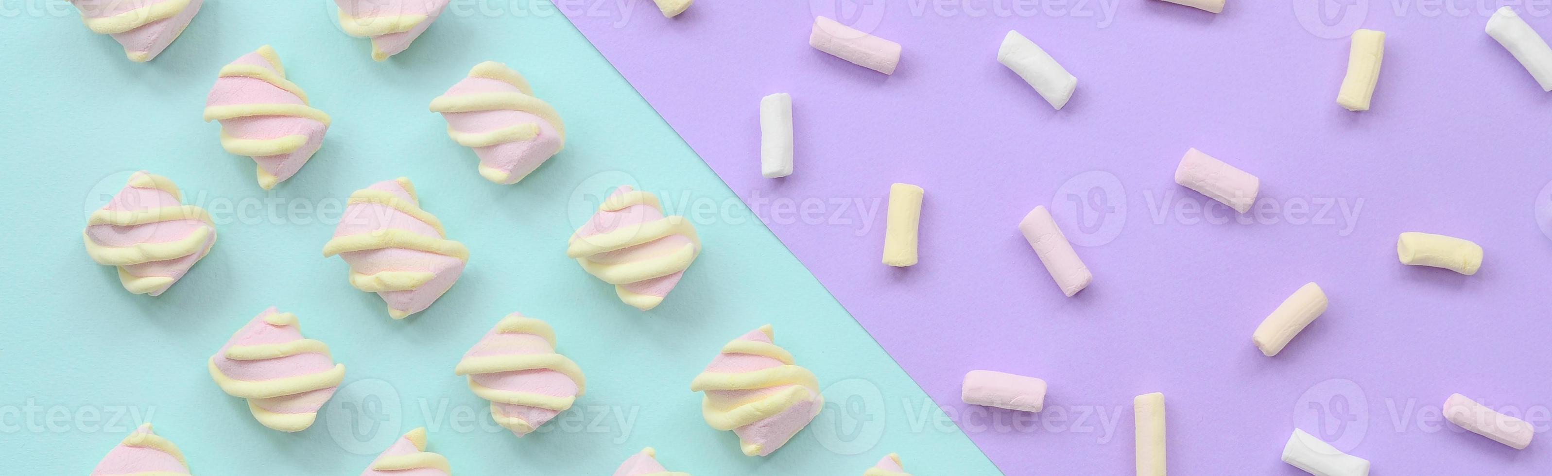 Colorful marshmallow laid out on violet and blue paper background. pastel creative textured pattern. minimal photo