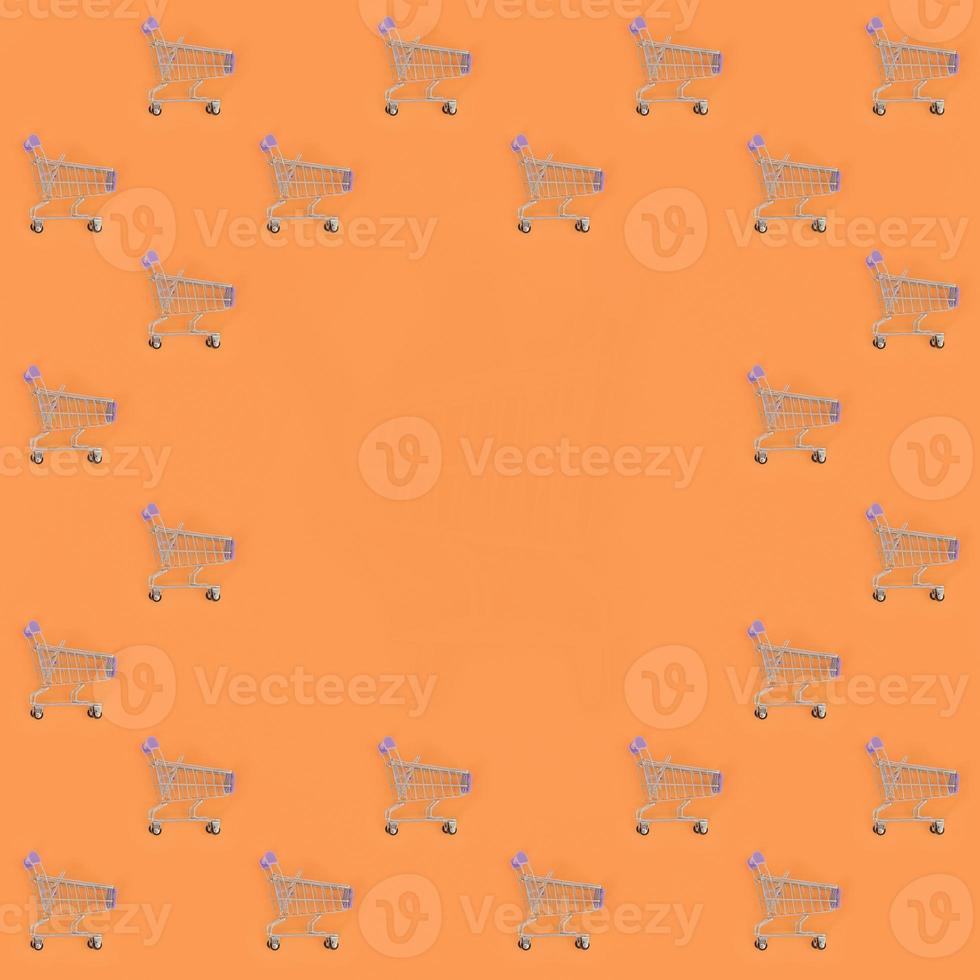Shopping addiction, shopping lover or shopaholic concept. Many small empty shopping carts perform a pattern on a pastel colored paper background. Flat lay composition, top view photo