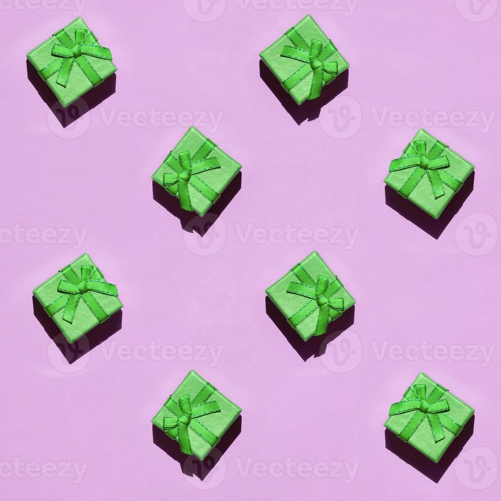 Many small green gift boxes on texture background of fashion trendy pastel pink color paper photo