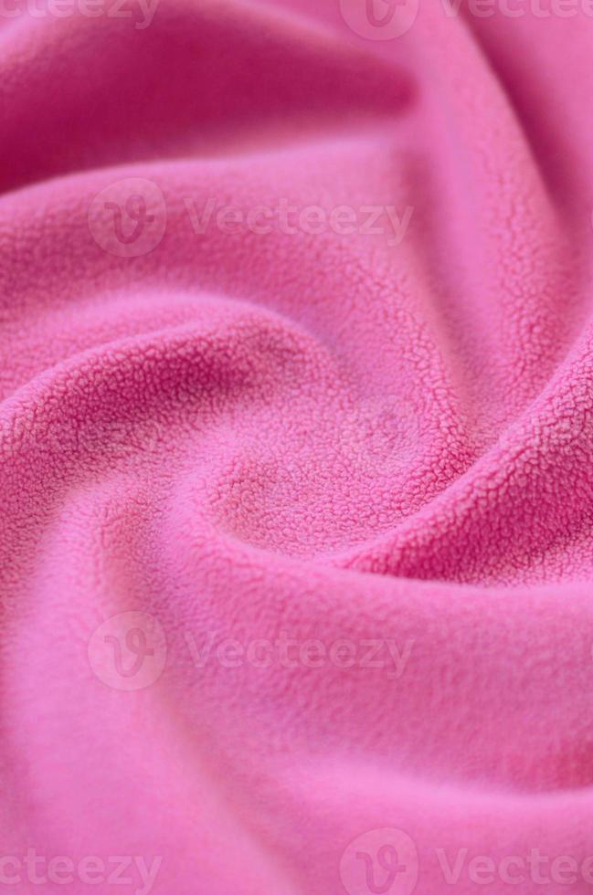 The blanket of furry pink fleece fabric. A background of light pink soft plush fleece material with a lot of relief folds photo