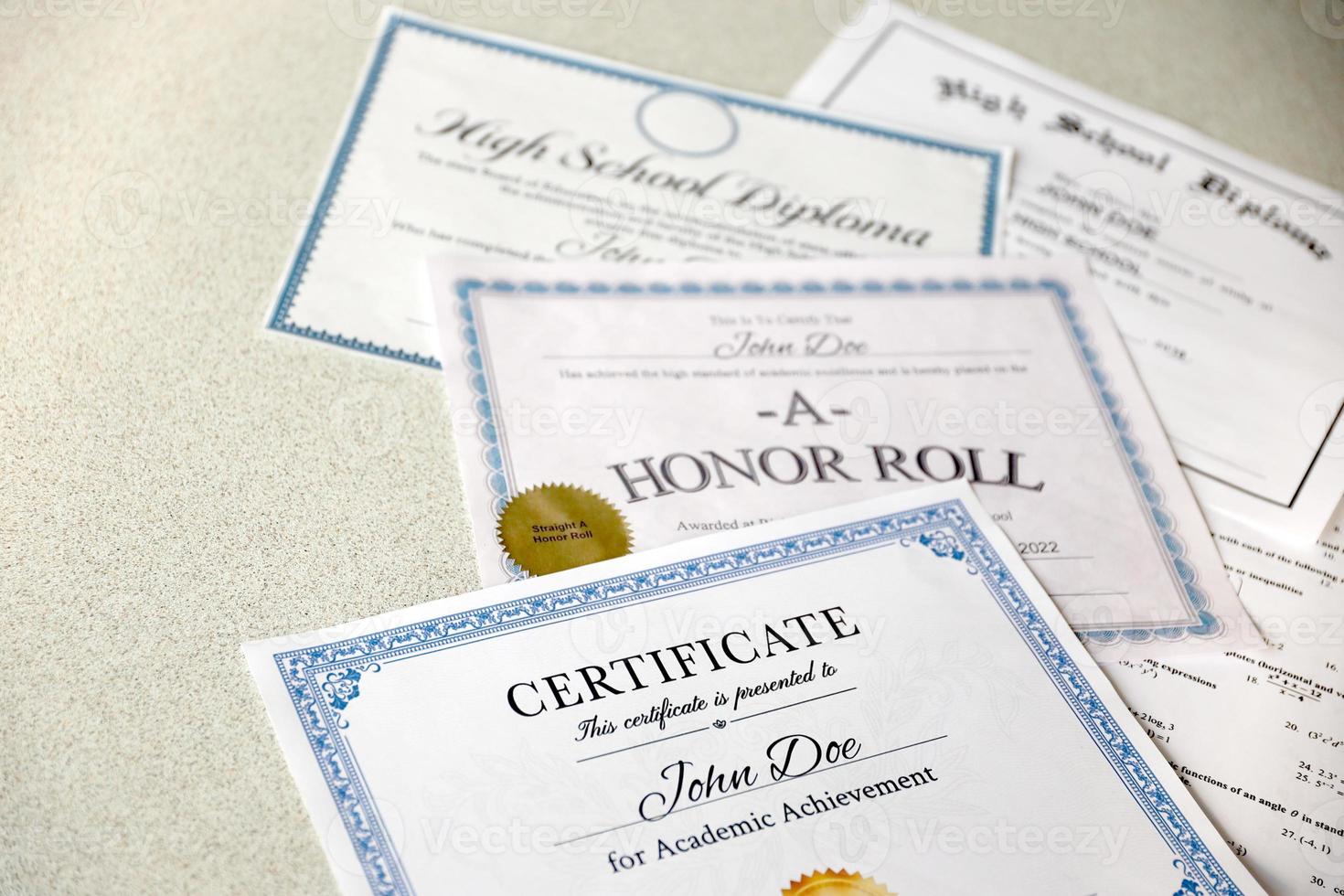 A honor roll recognition, certificate of achievement and high school diploma lies on table. Education documents photo