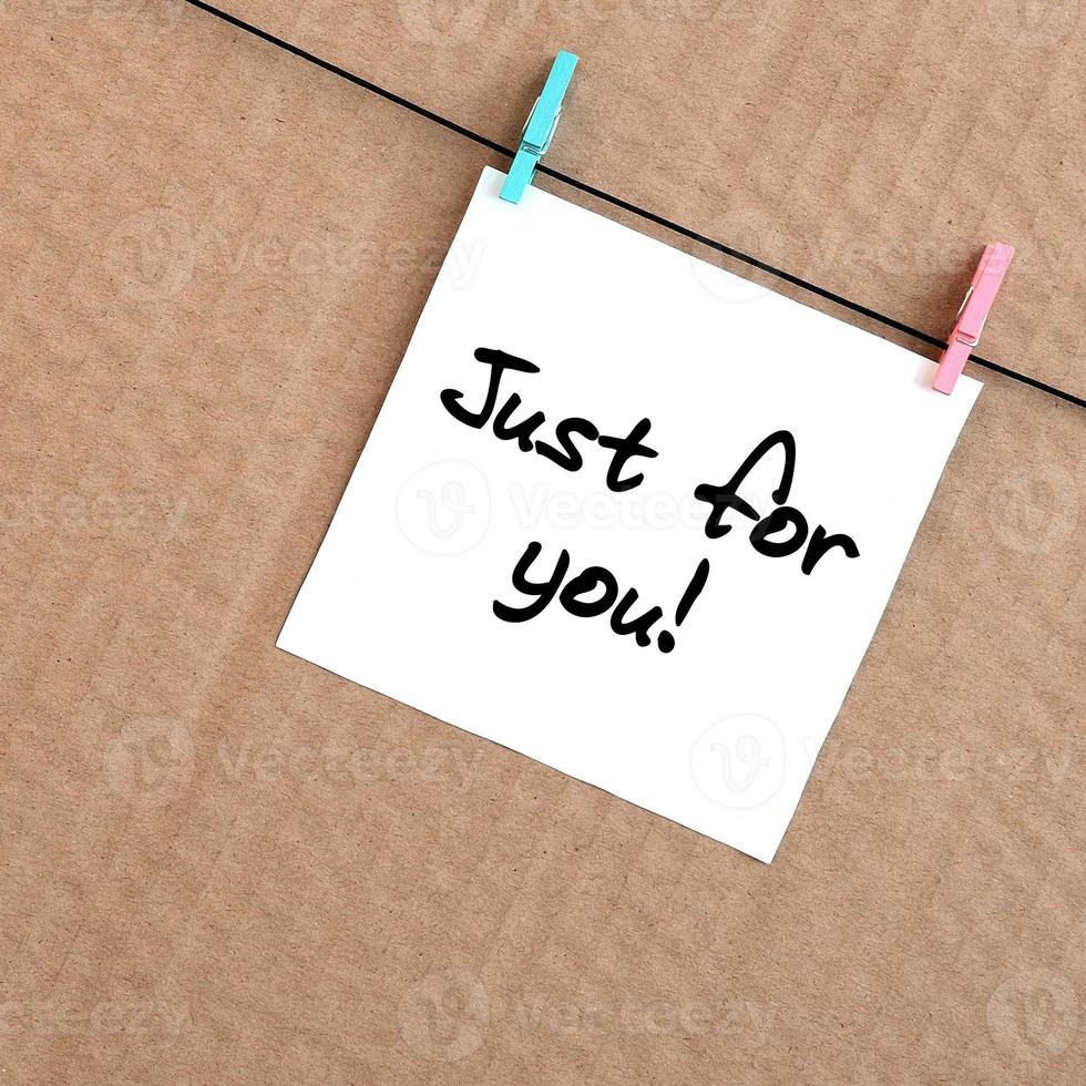 Just for you Note is written on a white sticker that hangs with a clothespin on a rope on a background of brown cardboard photo