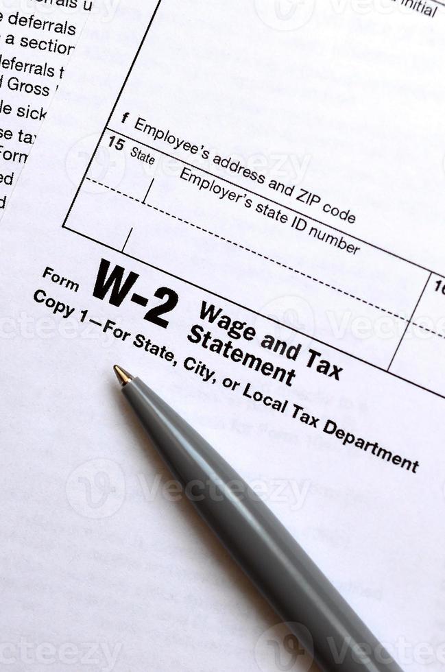 The pen lies on the tax form W-2 Wage and Tax Statement. The time to pay taxes photo