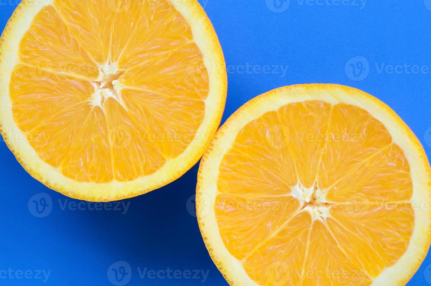 Top view of a several orange fruit slices on bright background in blue color. A saturated citrus texture image photo